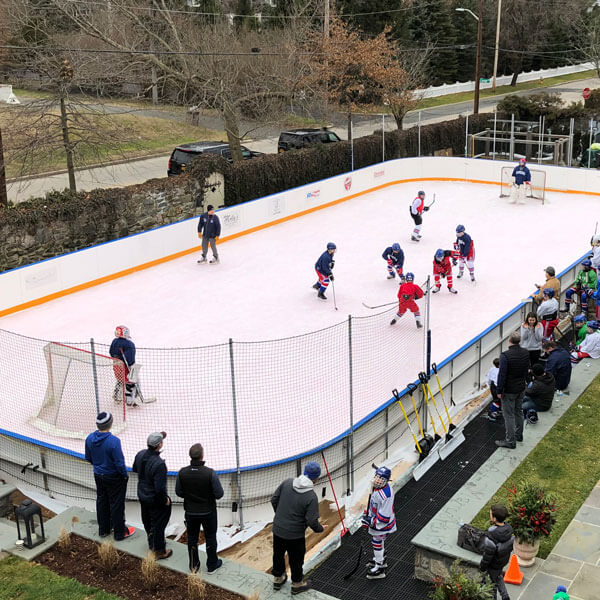 young kids playing hockey on a backyard rink